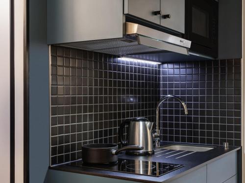 a kitchen with a sink and a pot on a stove at Aparthotel Adagio access Hamburg in Hamburg