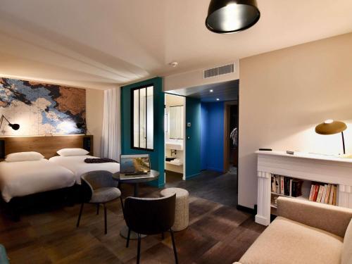 サン・ナゼールにあるibis Styles Saint Nazaire Centre Gareのベッド2台と暖炉のあるホテルの部屋