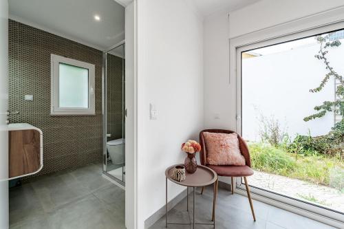 a bathroom with a chair and a table and a window at Villa Adão Lobo in Adão Lobo