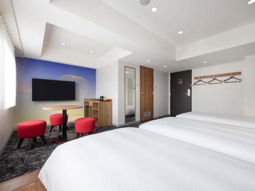 a hotel room with a bed and a desk and a tv at ibis Styles Kyoto Shijo in Kyoto