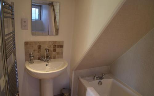 een badkamer met een wastafel en een ligbad naast een wastafel bij Hope Cottage in Stroud