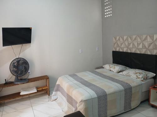 a bedroom with a bed and a fan and a tv at Kitinete encantadora in Arraial do Cabo