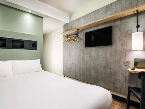 a bedroom with a bed and a wall with a tv at ibis budget Manchester Airport T2 in Hale