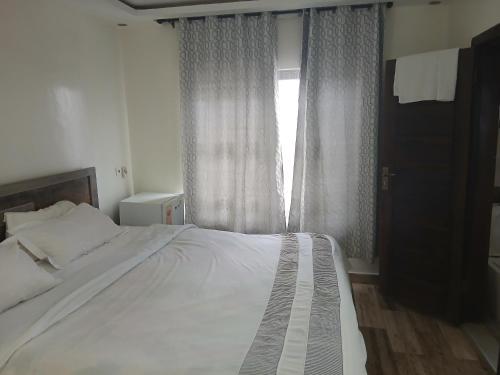 a bedroom with a large white bed and a window at MV Grand Hotel in Apenkwa