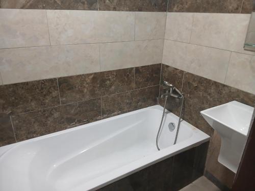 a bathroom with a white bath tub and a sink at MV Grand Hotel in Apenkwa