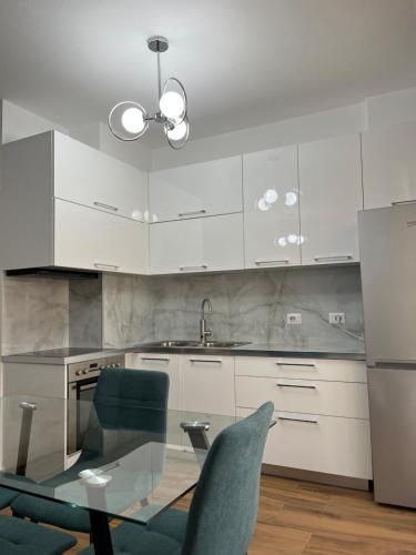 eine Küche mit weißen Schränken und einem Glastisch in der Unterkunft Elena residence in Tirana