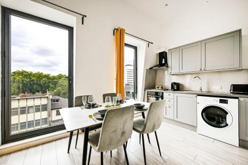 a kitchen with a table and chairs and a large window at Modern Ealing Broadway Apt -2 mins To Tube & Well-Equipped in Ealing