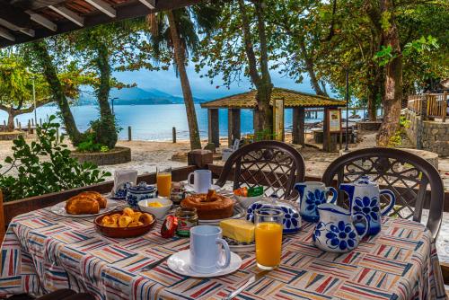 a table with food on it with a view of the ocean at Villa do Portinho - Casas em frente à Praia in Ilhabela