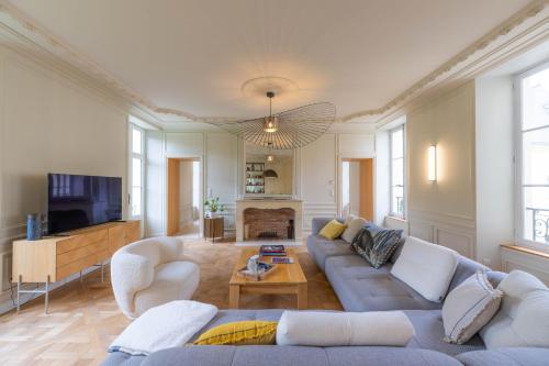 ein Wohnzimmer mit Couch und Fernseher in der Unterkunft Historic 18th-Century Mansion - 3 BR - Bayeux - Garden & Museums Nearby in Bayeux