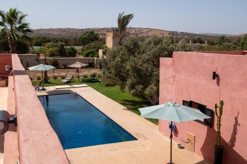 Una piscina con una sombrilla al lado de una casa. en CASA MISASHA nature, calme, bio et vos repas préparés par notre cuisinière, en Essaouira
