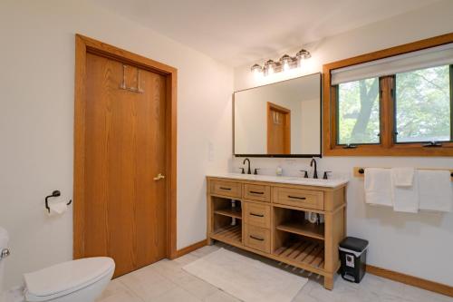 a bathroom with a sink and a toilet and a mirror at Rice Lake Cabin Retreat with Red Cedar Lake Access! in Rice Lake