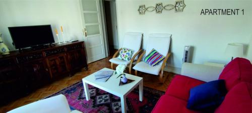 a living room with a red couch and two chairs at Charming Family Apartment in Lisbon