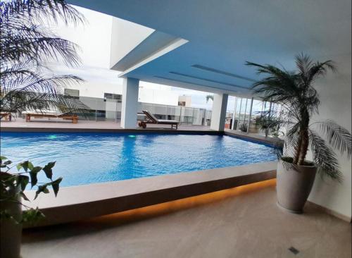 a large swimming pool in the middle of a building at APARTAMENTO COMODO EN EQUIPETROL TOTALMENTE AMOBLADO CON 2TVS CON NETFLIX, PISCINA TEMPERADA, GYM, CINE y PARQUEO cerca de Mall Ventura, Cines, restaurants y supermercados in Santa Cruz de la Sierra