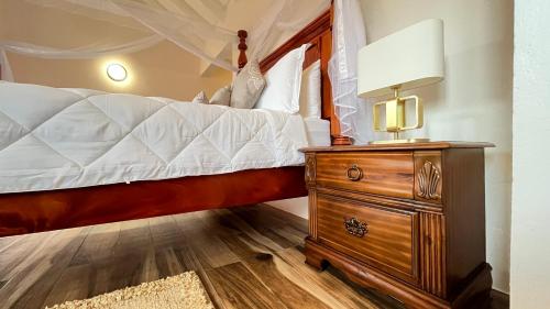 a bedroom with a bed and a dresser with a lamp at Tranquil Villas in Soufrière