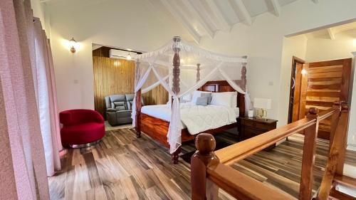 a bedroom with a canopy bed and a red chair at Tranquil Villas in Soufrière