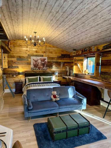 a living room with a blue couch and wooden walls at Willow Court Farm-Studio North & Petting Farm, 8 mins from Legoland & Windsor, 15 mins from Lapland UK in Windsor