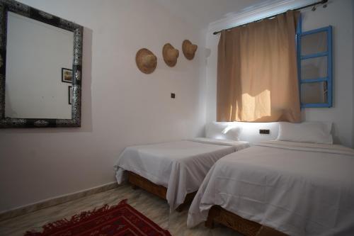 two beds in a room with a mirror and a window at Onda Surf in Taghazout