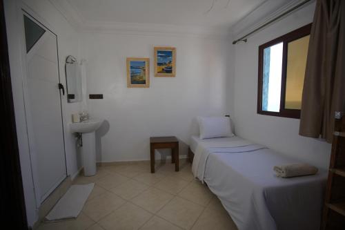 a small room with two beds and a sink at Onda Surf in Taghazout