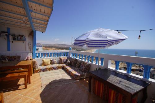 a balcony with a couch and an umbrella at Onda Surf in Taghazout