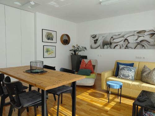 a living room with a table and a yellow couch at Art Appartement in Niedernsill
