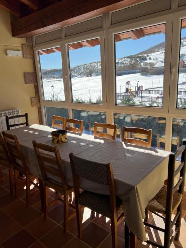 Un comedor con mesa y sillas y ventanas. en Casa rural LLOSA Planta PRIMERA y Planta BAJA, en San Salvador de Cantamuda