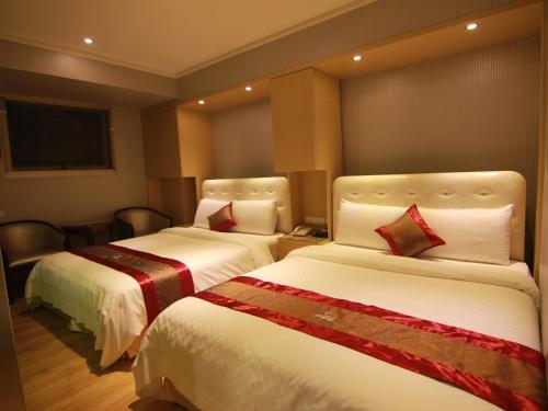 a hotel room with two beds and a television at Wonderful Hall Hotel in Xinzhuang