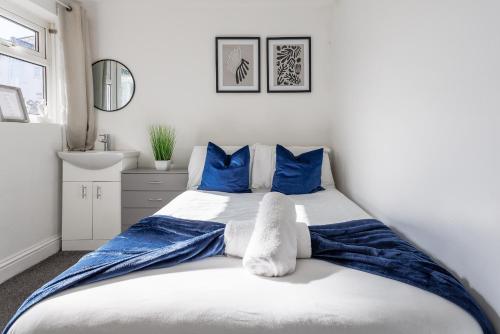 een slaapkamer met een bed met blauwe kussens en een wastafel bij 3 Bed House - Sleeps 5 - Parking - Wifi in New Brancepeth