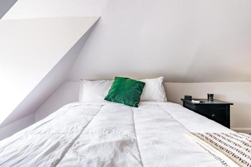 a white bed with a green pillow on it at Short North Convention King Bed Free Parking! in Columbus