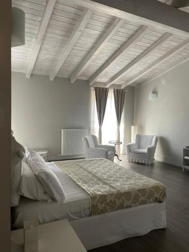 a bedroom with a large bed and two chairs at Locanda In Calvignano in Calvignano