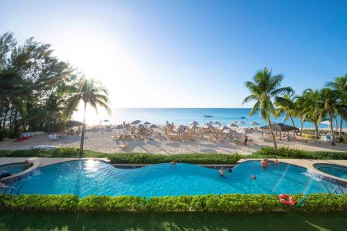 ジョージ・タウンにあるBeachcomber 08のヤシの木が茂るビーチの隣にある大きなスイミングプール