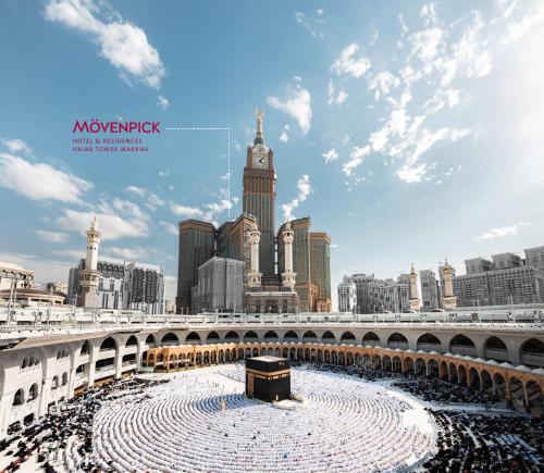 a large crowd of people under a bridge with a clock tower at Movenpick Hotel & Residences Hajar Tower Makkah in Makkah