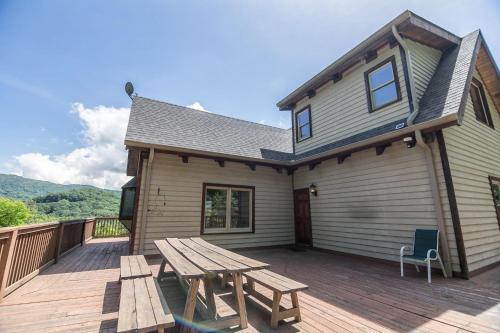 a wooden deck with a picnic table and a house at Stoneledge Manor in Banner Elk