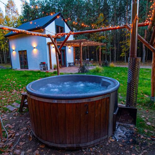 a large wooden hot tub in a yard with a house at Ranczo w lesie - domki z jacuzzi in Ożarów