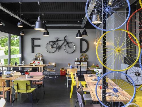 a restaurant with tables and chairs and a bicycle on the wall at Mercure Reims Parc Des Expositions in Reims