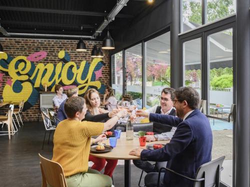 a group of people sitting around a table in a restaurant at Mercure Reims Parc Des Expositions in Reims