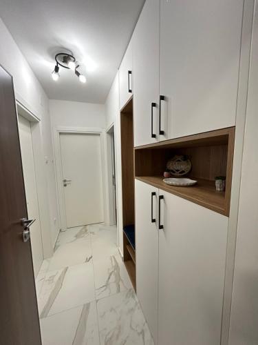 a white kitchen with white cabinets and marble floors at Apartman Maja in Budžak