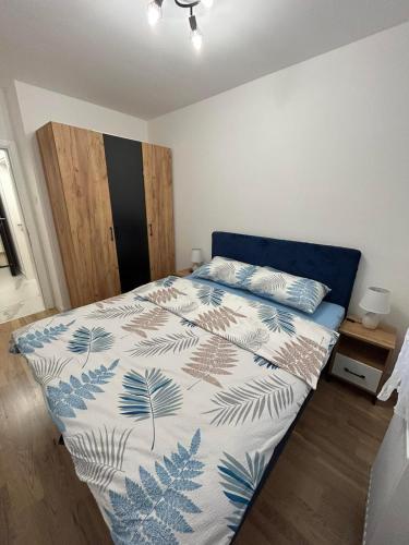 a bedroom with a bed with a blue and white comforter at Apartman Maja in Budžak