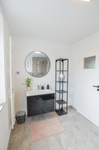 a white bathroom with a sink and a mirror at KasselRooms Loft - Friedrichsplatz in Kassel