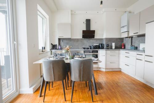 a white kitchen with a table and chairs at KasselRooms Loft - Friedrichsplatz in Kassel