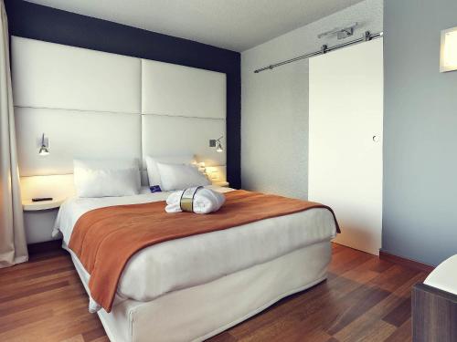 a bedroom with a large bed with a large headboard at Mercure Brive in Ussac
