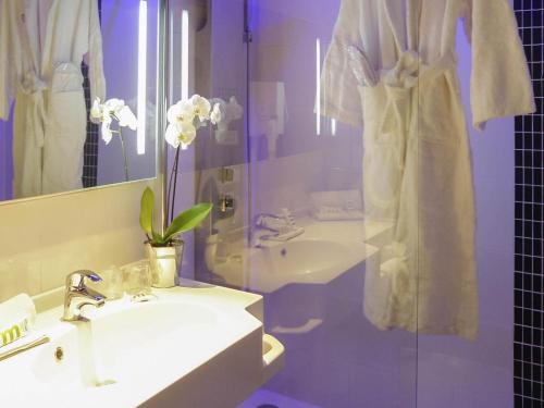 a bathroom with a sink and a shower with towels at Mercure Brive in Ussac