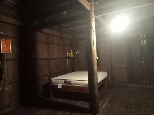 a bed in a wooden room with a light at Sconvolts Homestay in Kratie