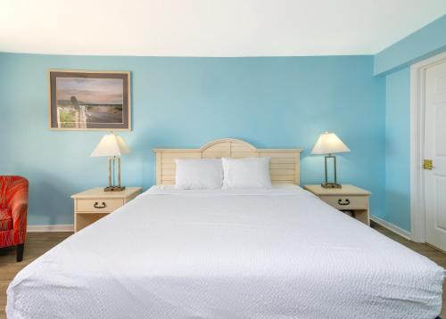 a bedroom with a large bed with blue walls at Drifting Sands Oceanfront Hotel in Ship Bottom