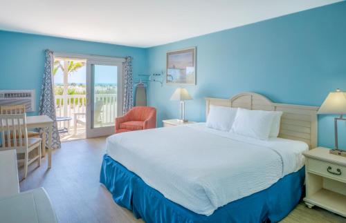 a bedroom with a large bed and a balcony at Drifting Sands Oceanfront Hotel in Ship Bottom