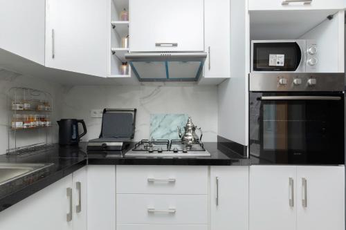 a white kitchen with a sink and a microwave at Jaws Wave ESSAOUIRA in Ghazoua