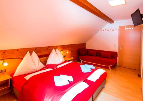 a bedroom with a red bed and a red couch at Gästehaus Biobauernhof Mandl in Murau