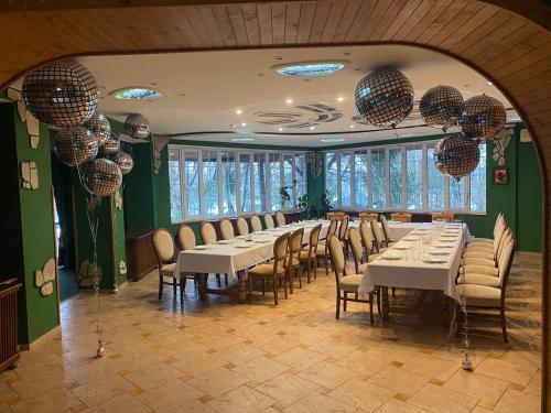 a dining room with white tables and chairs and windows at Hotel Orlinoye Gnezdo in Subottsi