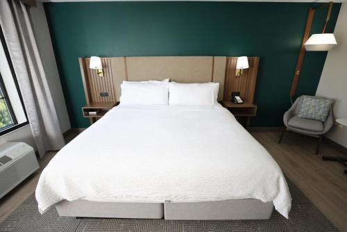 a bedroom with a large white bed and a chair at Holiday Inn Saint Louis-Fairview Heights by IHG in Fairview Heights