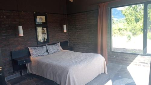 a bedroom with a bed and a large window at La Casita de Joaquin in Los Cipreses