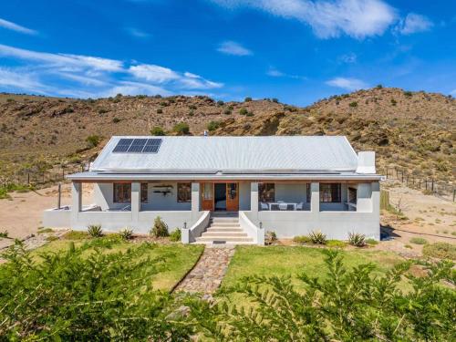 a white house with solar panels on the roof at Aardvark Bioreserve in Ladismith